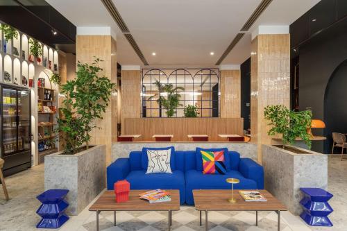 a lobby with a blue couch and tables at B&B HOTEL Milano Duomo Velasca in Milan
