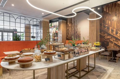 a bakery with cakes on a table in a room at B&B HOTEL Milano Duomo Velasca in Milan