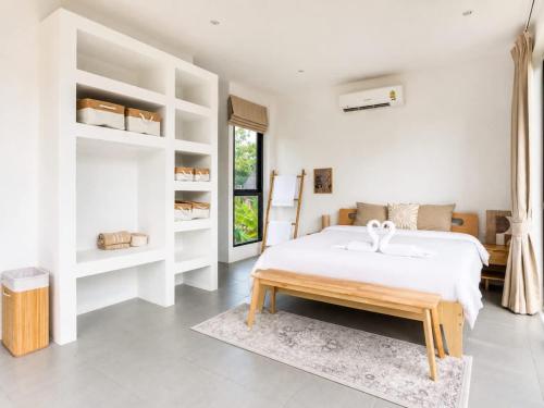 a white bedroom with a bed and a table at Beachside Villa in Ko Phangan