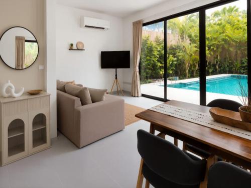 a living room with a table and chairs and a pool at Beachside Villa in Ko Phangan