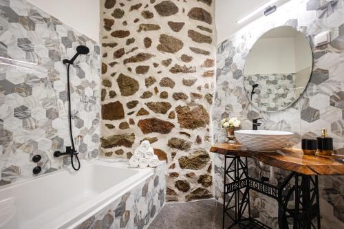 a bathroom with a stone wall and a tub and a sink at Jákób-Vár Vendégház in Füzér