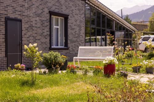 a bench in the yard of a house with flowers at FlowerHouse in Karakol