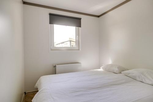 a white bed in a room with a window at Cube I stijlvol en licht 4 persoons chalet in Zennewijnen