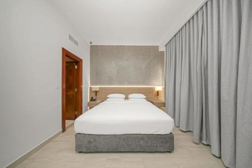 a bedroom with a large white bed and curtains at Premium Four Star Hotel by Blue Collection in Ras al Khaimah