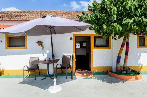a table with an umbrella in front of a house at VILA NATURA in Barreiro