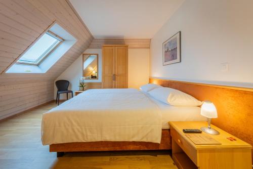 a bedroom with a bed and a desk and a window at Hôtel du Cheval Blanc - City center in Bulle