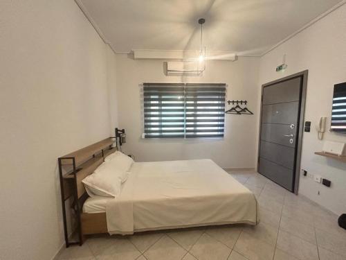 a bedroom with a bed with white sheets and a window at The Square Point in Komotini