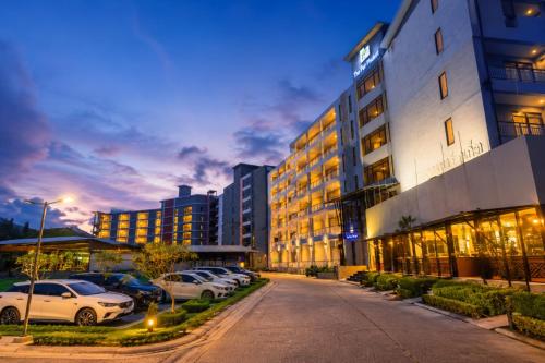 a building with cars parked in a parking lot at The Par Phuket Hotel in Kathu