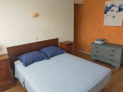 a bedroom with a bed with blue pillows and a dresser at les terrasses du Thouet in Parthenay