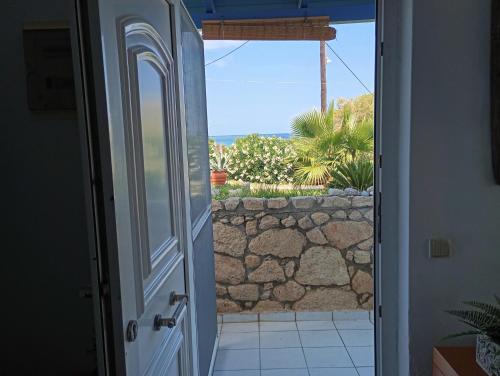 an open door to a patio with a stone wall at Sunset Beach House Posseidi in Possidi