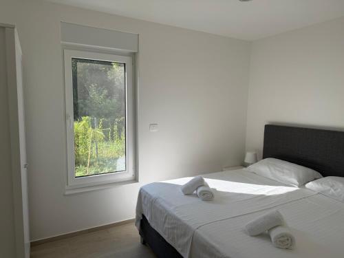 a white bedroom with a bed and a window at Baden Resort Bašanija, Umag-with Sea View, Parking and 300m from the beach in Bašanija