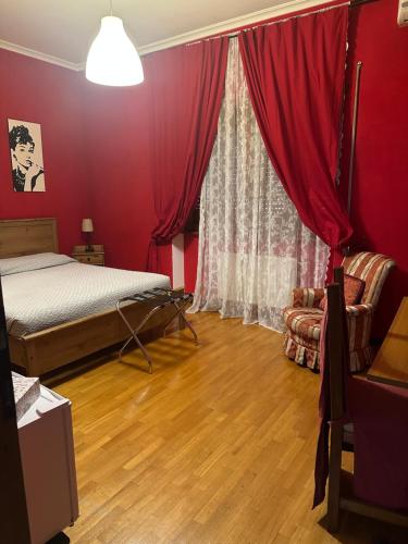 a bedroom with red walls and a bed and a window at La Maison Blanche in Borghesiana 
