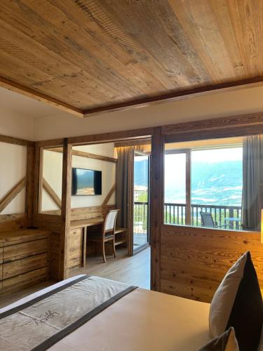 a bedroom with a bed and a desk with a balcony at Lady Maria Hotel Wellness & Resort in Fondo