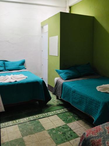 a bedroom with two beds and a green wall at Hotel Antequera in Oaxaca City
