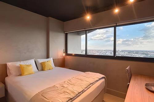 a bedroom with a bed and a large window at Vertigo Premium Studios in Campo Grande