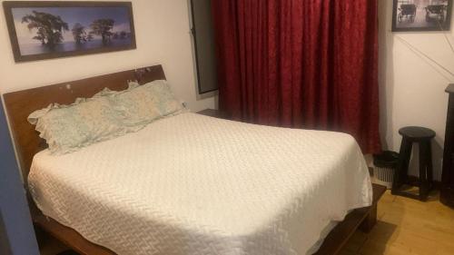 a bedroom with a white bed with a red curtain at Habitaciones Ciudad de la Luna Chia in Chía