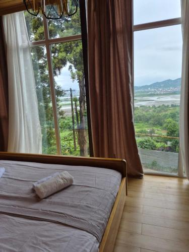 a bed in a room with a large window at Hillside House Overlooking Batumi in Charnali