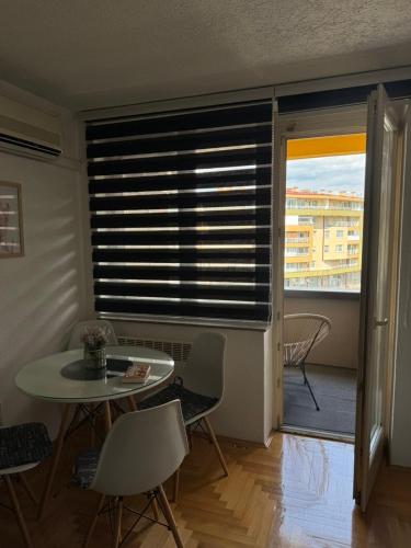 a living room with a table and a window with blinds at Capital apartman in Visoko