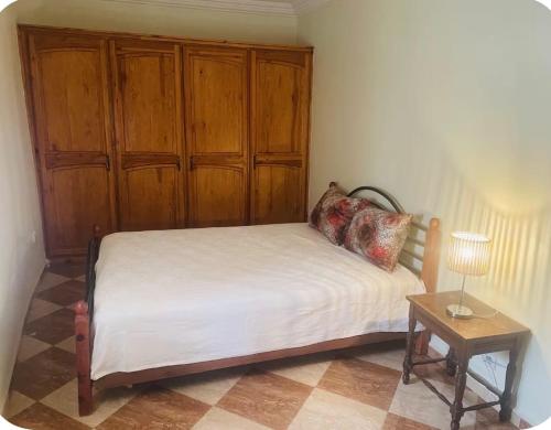 a bedroom with a bed with a wooden cabinet at Quiet house with pool in Aïn Harrouda