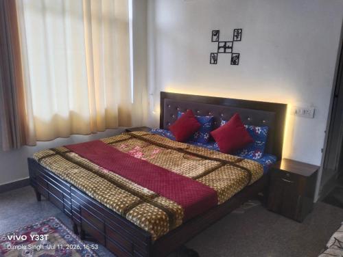 a bedroom with a bed with red pillows on it at Dhananjay home stay in Dharampur