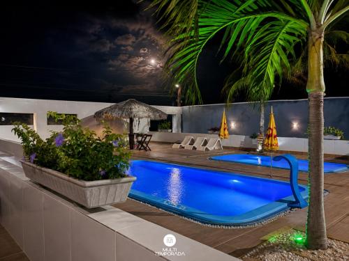 a swimming pool at night with a palm tree at Pousada On the Beach - Aquiraz/CE in Aquiraz