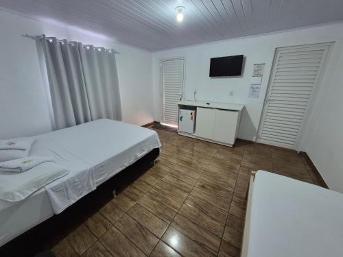 a hotel room with a bed and a television at Pousada Maria in Maravilha
