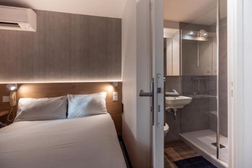 a bedroom with a bed and a bathroom with a sink at The Originals Access, Hôtel Bordeaux Lac in Bruges