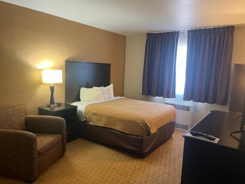 a hotel room with a bed and a chair at Chieftain Conference Center in Carrington
