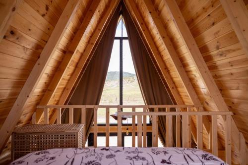 a bedroom with a large window in a wooden cabin at Hedwig cottages 1 in Njegovuđa