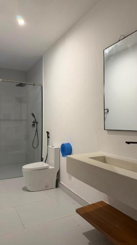 a white bathroom with a shower and a toilet at Coral by Ivory Hotels in Mombasa