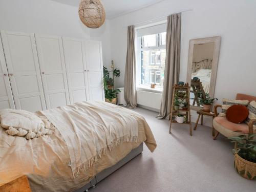a bedroom with a bed and a chair and a mirror at Snowdrop Cottage in Keighley