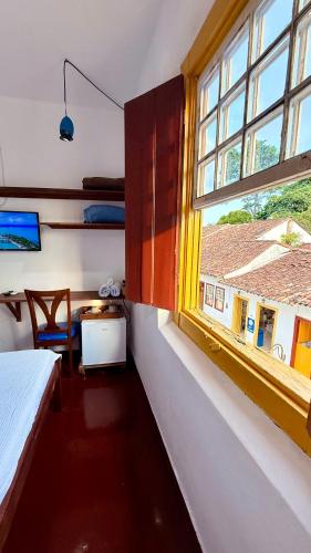 a bedroom with a window and a bed and a table at Pousada Café e Prosa Centro Histórico Paraty in Paraty