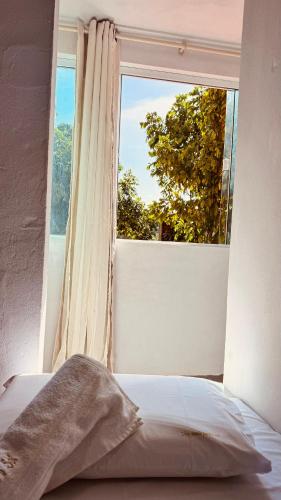 a bed in front of a window with a view at Uma Janela Para o Sol in Morro de São Paulo