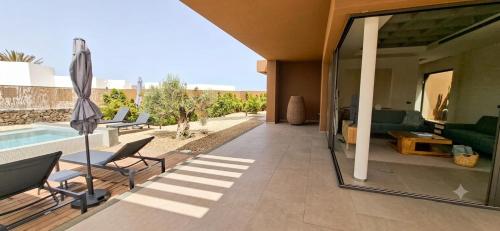 a patio with a pool and chairs and an umbrella at Natural Beatriz Luxury Villa Baby Package Included in Lajares