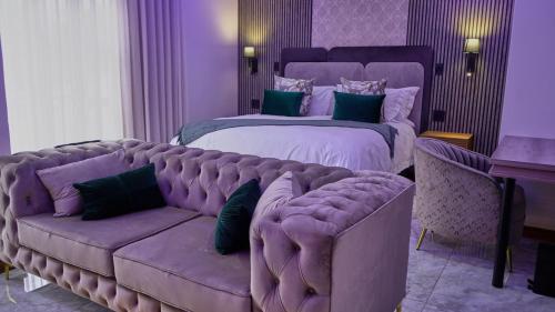 a purple bedroom with a bed and a couch at The ATRIUM BOUTIQUE HOTEL in Polokwane
