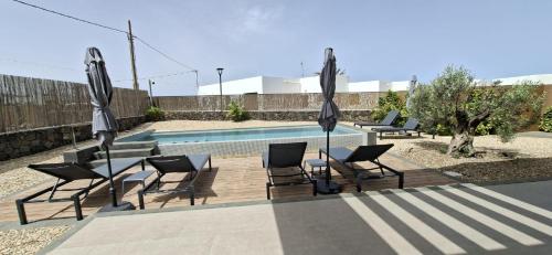 a group of chairs and umbrellas next to a pool at Natural Beatriz Luxury Villa Baby Package Included in Lajares