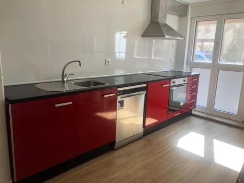 a kitchen with red cabinets and a sink at Entre Micelios in Vinuesa