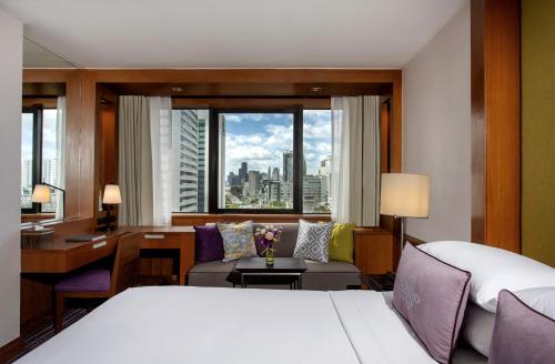 バンコクにあるThe Sukosol Hotelのベッドと机と寝室のあるホテルの部屋