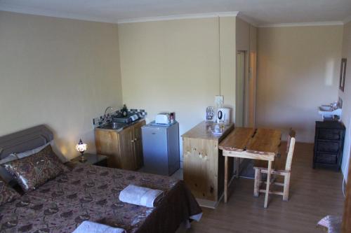 a bedroom with a bed and a kitchen with a table at Denmark Farm Stay in Cradock