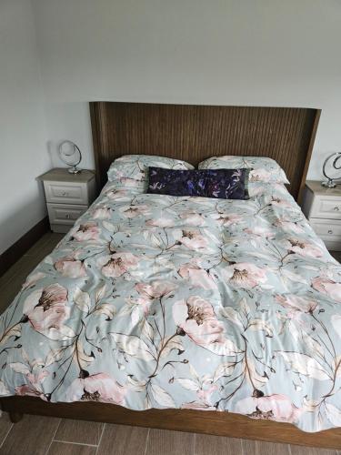 a bed with a floral comforter and two night stands at Suaimhneas in Lahinch