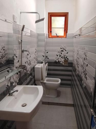 a bathroom with a toilet and a sink and a window at Papa's Resort Dunhinda in Hinnarangahakumbura