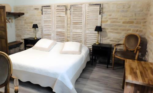 a bedroom with a white bed and two chairs at Gîte La Maison Du Parc in Argilly