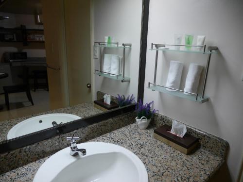 a bathroom counter with a sink and a mirror at New Manila Suites in Manila