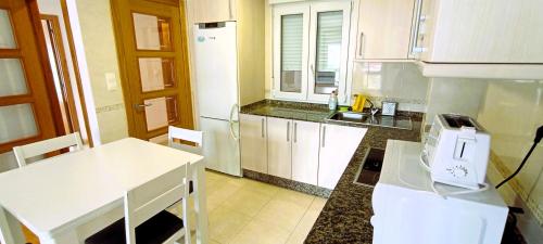 a kitchen with white cabinets and a white table at EnSAN CIPRIAN Playas y Relax in San Ciprián