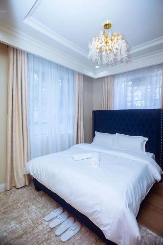 a bedroom with a large white bed with a chandelier at Elazoh Apartments in Kisumu