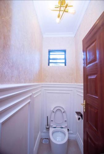 a bathroom with a toilet with a ceiling fan at Elazoh Apartments in Kisumu