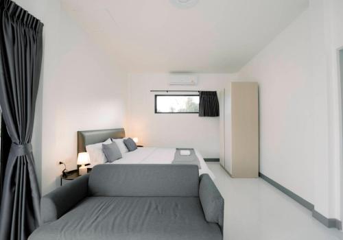 a bedroom with a bed and a couch and a window at NS Khaolak Resort in Khao Lak