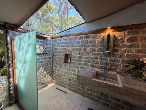 a bathroom with a stone wall and a sink at Oca House in Búzios