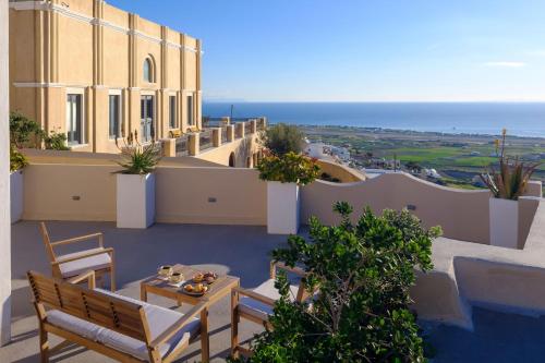 a balcony with a table and chairs and the ocean at Themis Goddess Cave Suites in Santorini