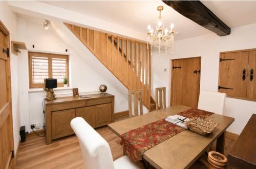 a dining room with a table and a staircase at Lennon cottage in Hale
